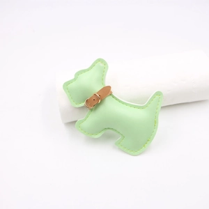 Close-up of light green leather puppy bag charm with yellow stitching and gold metal buckle