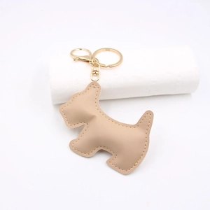 Close-up of beige leather puppy keychain with detailed stitching and golden lobster clasp