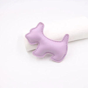 Close-up of purple leather dog-shaped pendant with visible stitching and premium texture