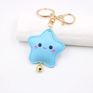 Close-up of light blue star keychain with cute smiley face and golden bell detail