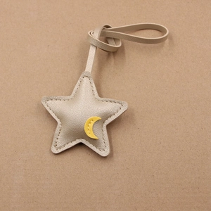 Detailed view of champagne gold leather star pendant with moon motif and strap