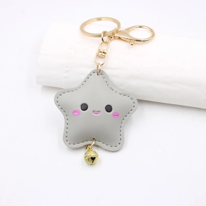 Close-up of gray leather star keychain with cute smiley face and golden bell detail