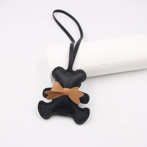 Detail view of a black leather bear pendant with fine stitching and brown bowknot