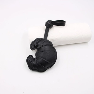Detail of black croissant leather bag charm with visible topstitching and adjustable strap