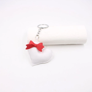 Detail view of heart-shaped white leather keychain with a red bow and silver metal chain