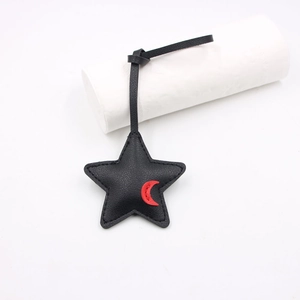 Star-shaped black faux leather bag charm with red crescent detail and fine stitching