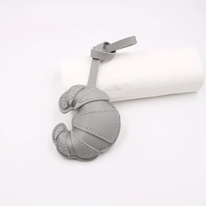 Close-up of grey leather croissant-shaped charm with white contrast stitching details
