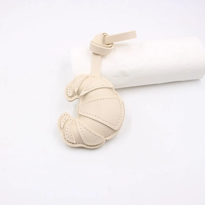 Detail of cream croissant leather pendant featuring pebble grain texture and neat stitching