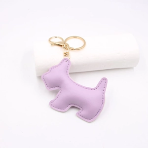 Macro view of purple leather dog bag charm with detailed stitching and gold key ring