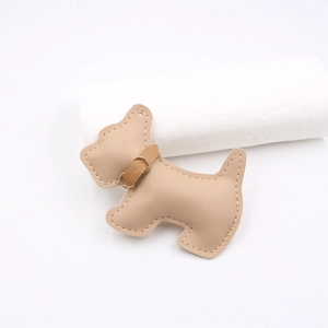 Detailed view of light brown leather dog charm with manual stitching and gold metal buckle