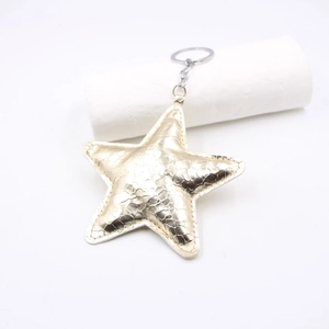 Detail of star-shaped golden faux leather keychain with textured snake skin finish