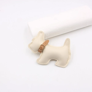 Close-up of cream leather dog charm featuring lychee grain texture and fine stitching