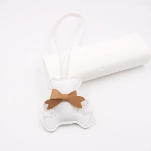Close-up of white PU leather bear tag with brown bow and fine stitching details