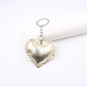 Detail of champagne gold heart-shaped leather keychain with textured finish and silver ring