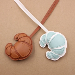 Detailed view of handmade leather croissant charms in brown and mint green colors