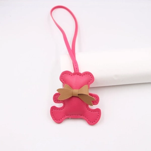 Detailed view of rose pink leather bear charm with brown bow and long lanyard accessory