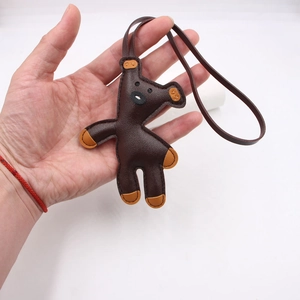 Detailed close-up of a handmade brown leather bear bag charm with orange accents