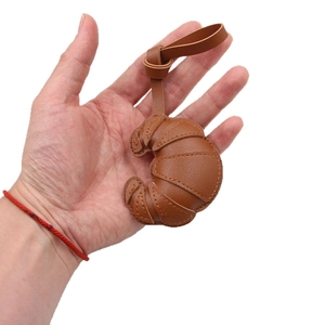 Faux leather croissant bag charm in brown with realistic grain texture and lanyard
