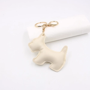 Close-up of cream leather dog keychain with gold hardware and fine stitching detail
