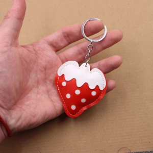 Close-up of strawberry leather keychain with red polka dots and silver metal clasp