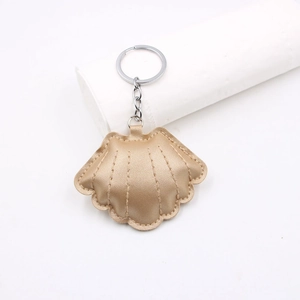 Detailed close-up of champagne gold leather shell keychain with lychee texture and silver ring