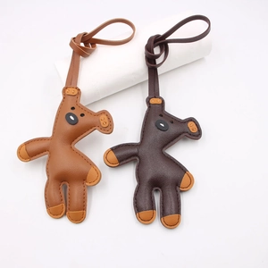 Handmade leather giraffe bag charms in tan and dark brown with stitching and leather straps