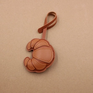 Brown leather croissant bag charm with handmade stitching and matching lanyard
