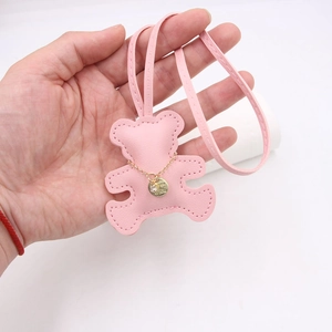 Detail of pink faux leather bear pendant with gold chain and strap on hand