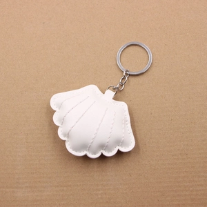Detail of white PU leather seashell keychain with quilted stitching and silver metal ring