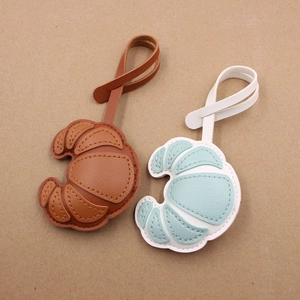 Litchi pattern leather croissant bag charms in brown and blue with stitching detail