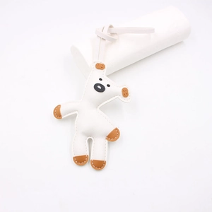 Detailed close-up showing white leather cartoon dog charm with brown ear accents and stitching