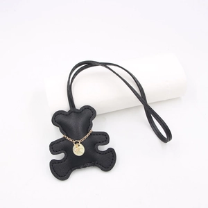 Detail of black leather bear bag charm with fine stitching and gold chain pendant accessory