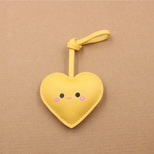 Vue détaillée du pendentif cœur jaune en cuir avec visage souriant et coutures précises