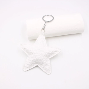 Macro shot of white faux snake leather star keychain with silver metal ring