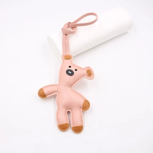 Detail of pink faux leather teddy bear bag charm with white stitching on white stand