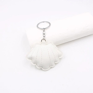 Detailed close-up of white shell keychain with PU leather texture and silver chain