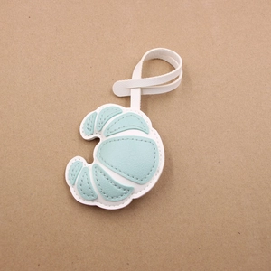Handcrafted croissant-shaped leather bag charm with white and mint green stitching detail