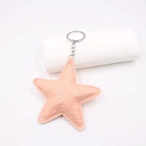 Macro detail of peach pink faux leather star keychain with snakeskin texture and silver ring