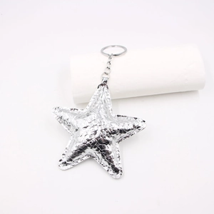 Close-up of sparkling silver star leather keychain with metallic ring and chain