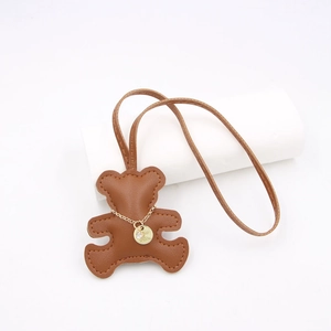 Close-up of brown textured leather bear charm with gold chain and rhinestone detail