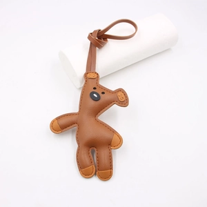 Detailed view of a brown leather cartoon bear bag charm with pebbled texture and lanyard
