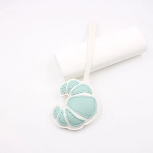Detail of croissant-shaped leather bag charm with white and mint green stitching