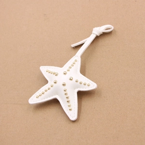 Détail d'un charm étoile de mer en cuir blanc avec clous dorés et cordon