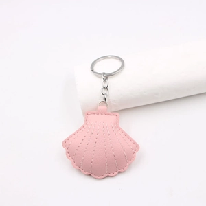 Detailed view of pink shell-shaped leather keychain with white stitching and silver metal ring