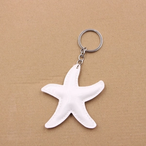 Close-up of white starfish keychain in shiny patent leather with detailed stitching