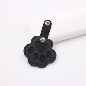 Detail of a black leather cat paw tracker case with silver metal snap buttons