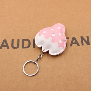 Macro detail of strawberry-shaped leather keychain with white polka dots and silver ring
