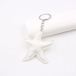 Close-up of white leather starfish keychain with silver metal ring and fine stitching detail