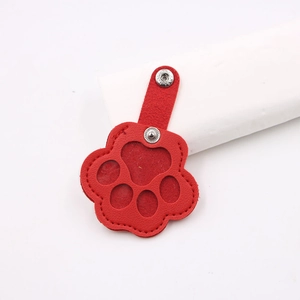 Close-up of red cat paw leather pet hair collector keychain with stitching and snap