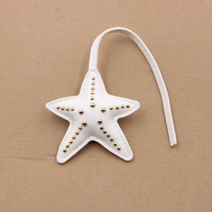 Détail d'un charm de sac étoile de mer en cuir blanc avec rivets dorés et surpiqûres